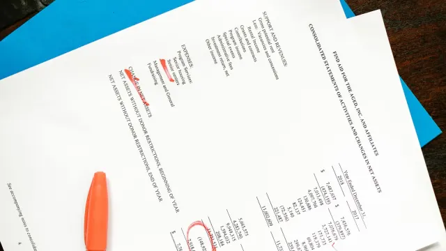 Documentos impressos com marcações em vermelho sobre a mesa.